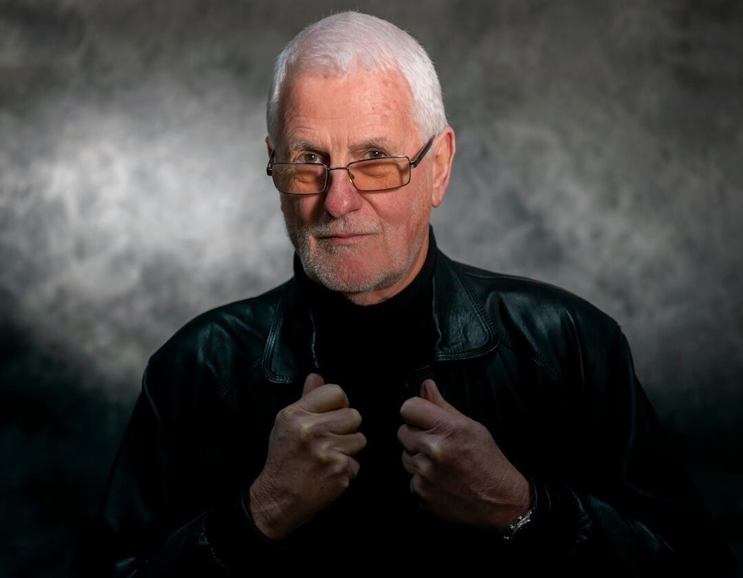 Studio portrait of a smiling older man with glasses